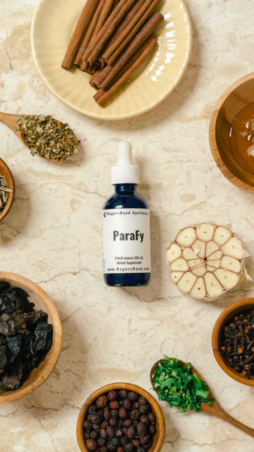 Parafy bottle surrounded by various herbs and spices on a textured surface