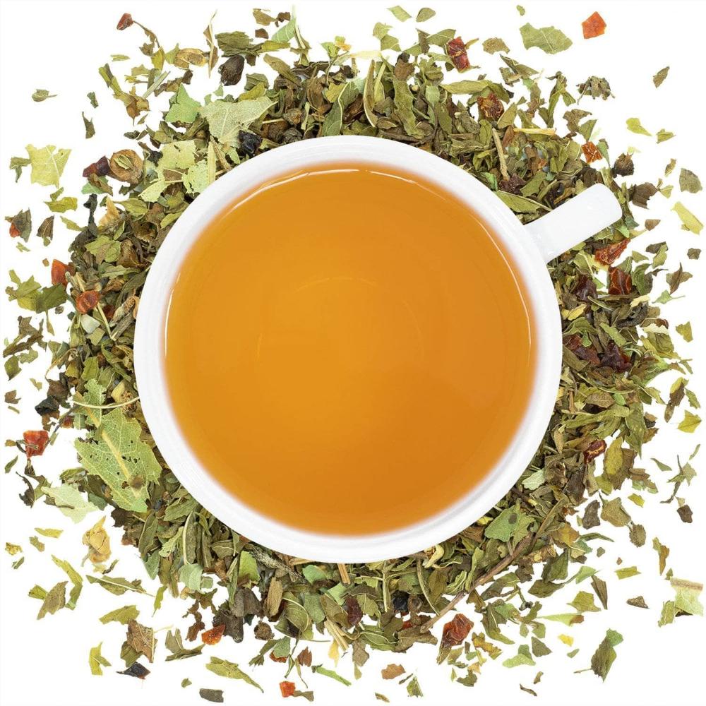 White cup of tea surrounded by dry tea leaves on a white background